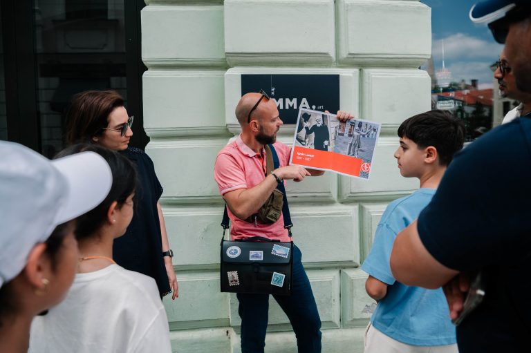 Guide in Bratislava showing the booklet to the clients during active school group tour to Slovakia