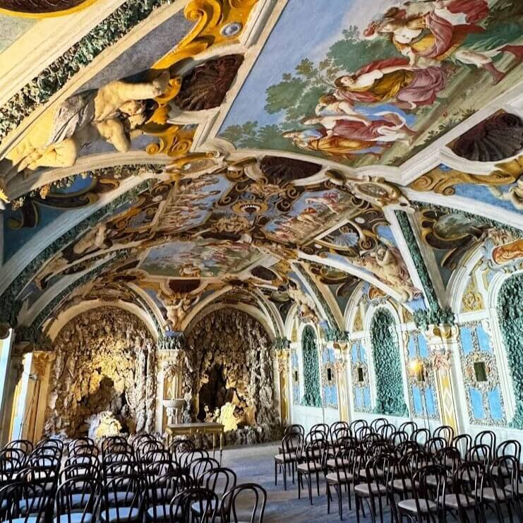 A beautifully decorated Baroque-style hall in Bratislava, featuring intricate frescoes on the ceiling, ornate sculptures, and elaborate stonework. Rows of chairs are set up, suggesting a venue for events or gatherings. This historic setting adds cultural charm to an incentive nature getaway in Bratislava.