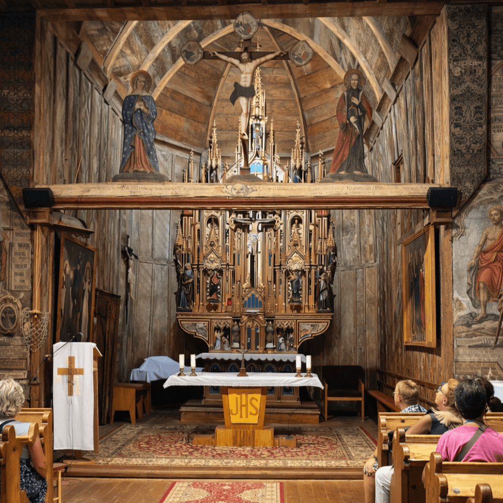 Small group tour in Slovakia – visitors inside a historic wooden church with ornate Gothic altar, part of UNESCO heritage pilgrimage program by E-TRAVEL.SK DMC