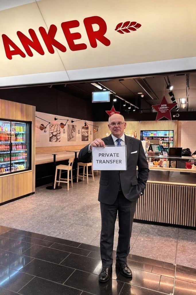 Professional private transfer driver holding a “Private Transfer” sign at Vienna Airport arrival area.