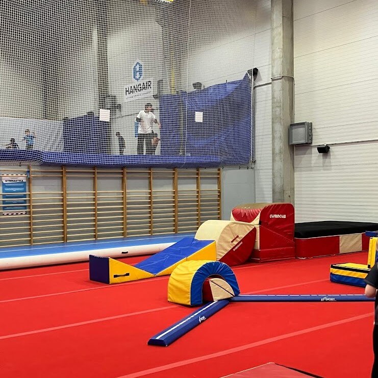 Modern gymnastics training facility in Bratislava featuring colorful foam equipment, wall bars, and spring floor area under HANGAIR branding - versatile MICE venue space for corporate team building and active events