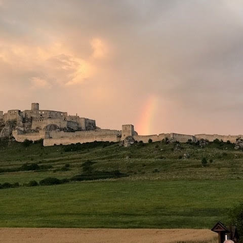 What a stunning shot — a rainbow over Spiš Castle at golden hour is pure magic! 🌈🏰 Let me embed it into the blog document right at the top of the Spiš Castle section.