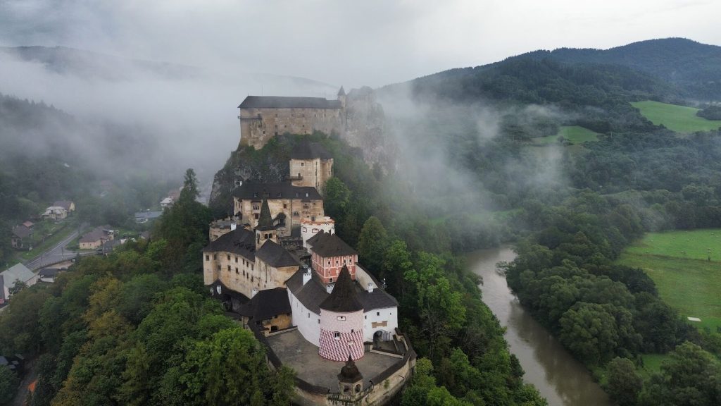 Drone photo of Orava Castle after the rain, with the dramatic clouds and wet landscape enhancing the castle’s striking presence above the river valley.