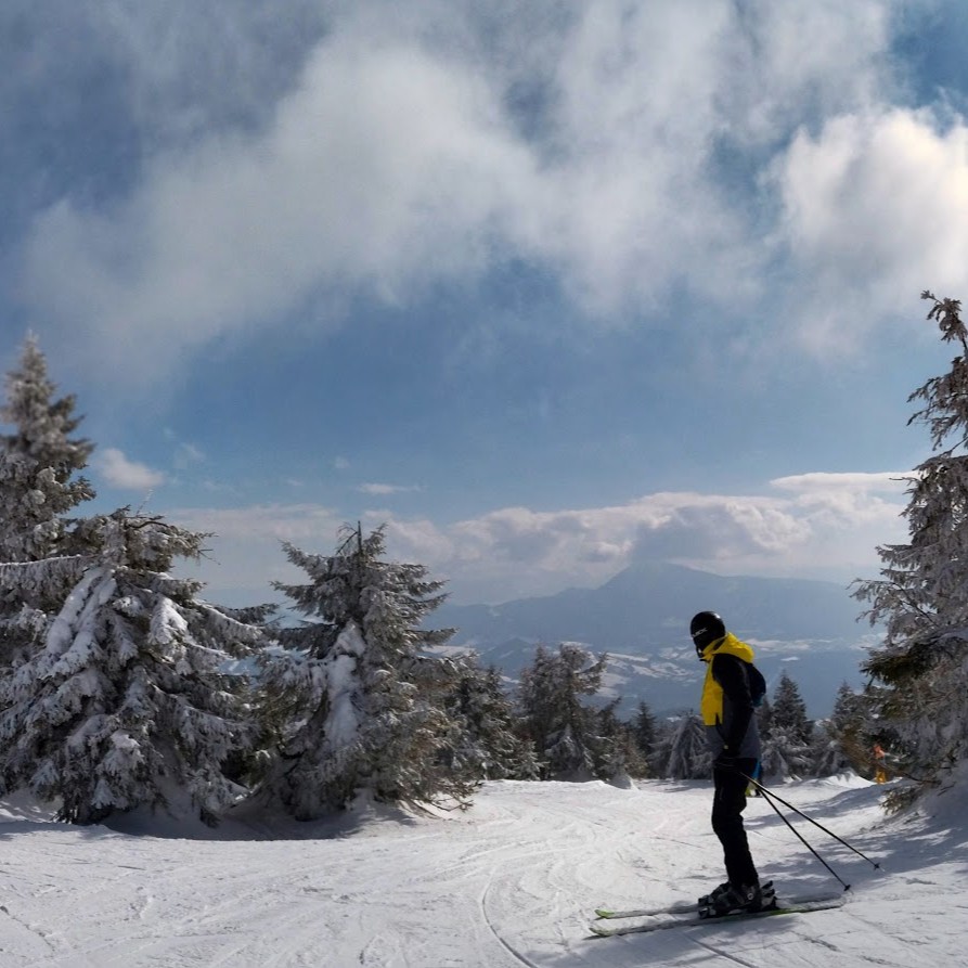 Skier at the summit of Kubínska Hoľa ski resort in Orava, Slovakia, with frost-covered spruce trees and a transmitter tower
